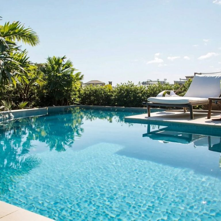 Ein einladender Pool mit Liegen, umgeben von üppigem Grün und klarem blauem Himmel.