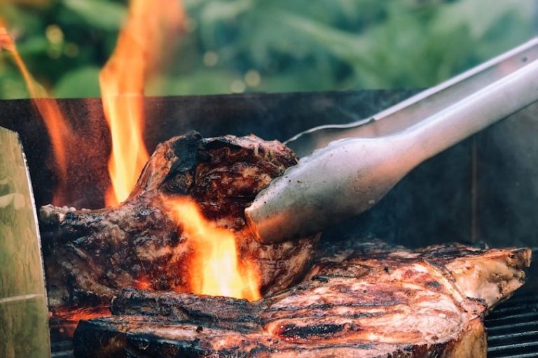 Saftiges Steak wird auf einem Grill mit Flammen gegrillt.