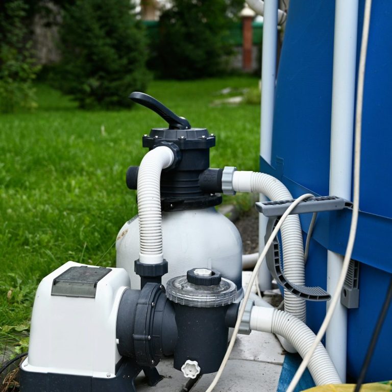 Druckpumpensystem mit Rohren vor einer grünen Rasenfläche.