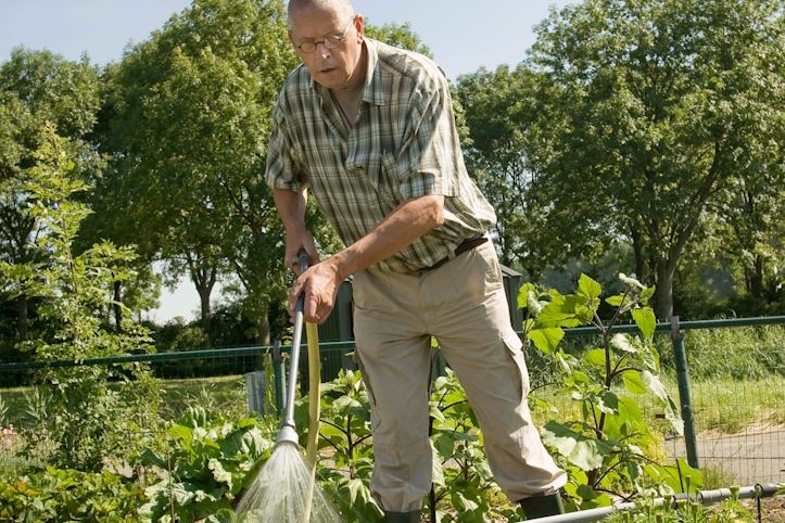 Handwerker in grüner Kleidung, der mit einem Besen einen Baustellenbereich reinigt.
