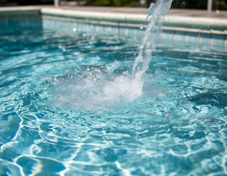 Sprudelndes Wasser in einem klaren Schwimmbecken mit Lichtreflexionen.